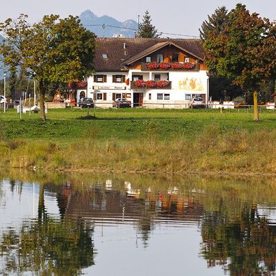 Holiday apartments Guesthouse Stefanie reflected in the clear water of Lake Forggensee